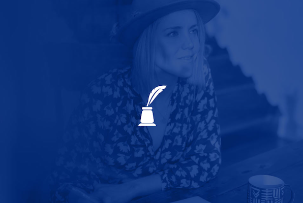 close up of a person holding a light bulb that is glowing and writing in a notebook.