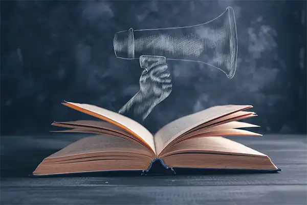 An opened book with a chalk drawn hand holding a loudspeaker sticking out of the book